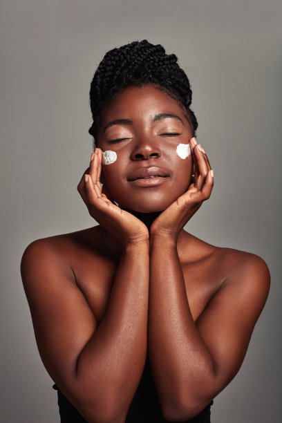 一个迷人的年轻女子在灰色背景上涂抹润肤霜的工作室镜头图片下载