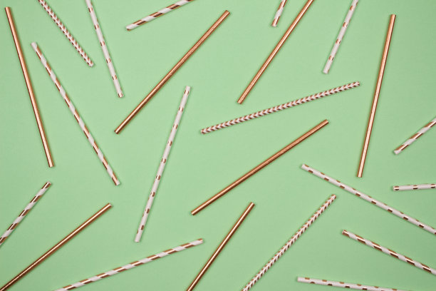 背景用不同的条纹纸制成，金黄色的吸管，绿色的背景与copyspace搭配。可降解环保吸管，用于夏日鸡尾酒图片下载