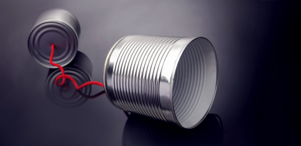 从一个锡罐里拿出一个手机玩具，放在光滑的黑色抛光的桌子上图片下载