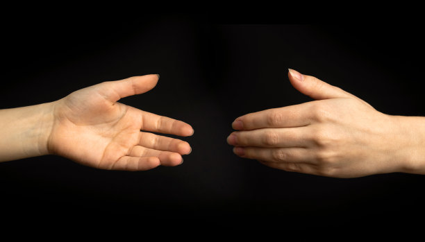 年轻女子在黑色背景上的握手手势。商业和专业的团队合作概念照片图片下载