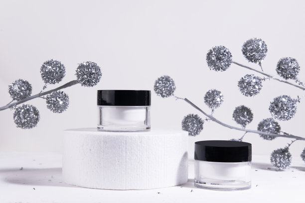 圣诞化妆品白色背景。模型的保湿化妆品产品在一个瓶子上圆筒讲台上的白色背景与圣诞装饰。美容或冬季护肤概念。给女性的圣诞礼物。本空间图片下载