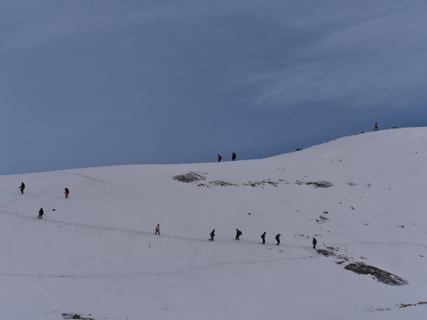 在加拿大落基山脉的亚伯达省的贾斯珀国家公园里，人们在伊迪丝卡维尔草地小径上的雪地上跟随脚印的剪影。图片下载