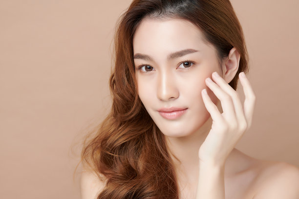 美丽的年轻亚洲女人干净新鲜的皮肤在米色背景，面部护理，面部治疗，美容，美容和水疗，亚洲女性肖像。素材图片