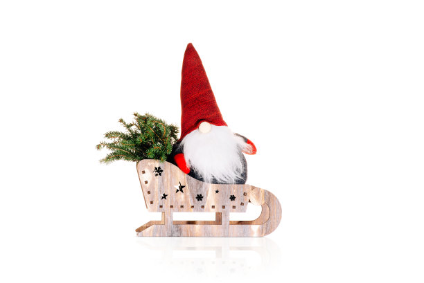 圣诞节和新年背景。简单简约的家居装饰。木制雪橇上装饰圣诞老人的玩具，背景上有一棵圣诞树。孤立的背景。圣诞组成。图片下载