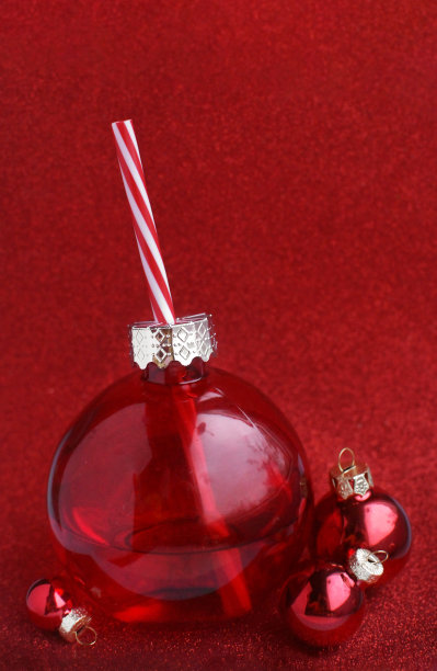 新年快乐或圣诞快乐。闪亮的红色圣诞树球和一个红色背景上有饮料的圆形玻璃球。贺卡或网站横幅。简约的节日装饰图片下载