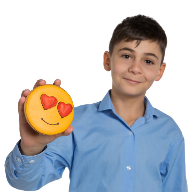 十几岁的孩子拿着蜂蜜姜饼，形状是一个带着气体的笑脸——心形，在白色的背景上，专注于饼干图片下载