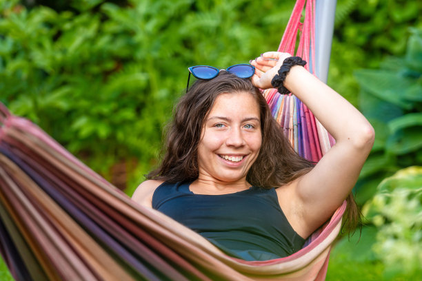漂亮的女性戴着太阳镜躺在花园的吊床上，放松，选择性的专注图片下载