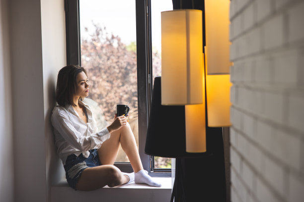 年轻女子坐在窗边放松图片下载