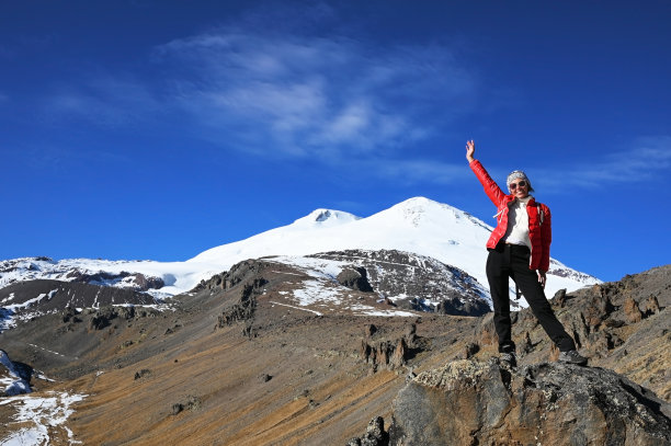 徒步旅行者年轻的女人在山顶反对蓝色的天空图片下载