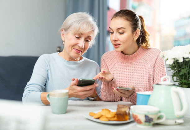 女孩用智能手机向感兴趣的妈妈展示照片图片下载