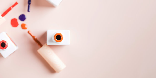 不同颜色的刷子明亮的指甲油瓶子在浅粉色的背景。图片下载