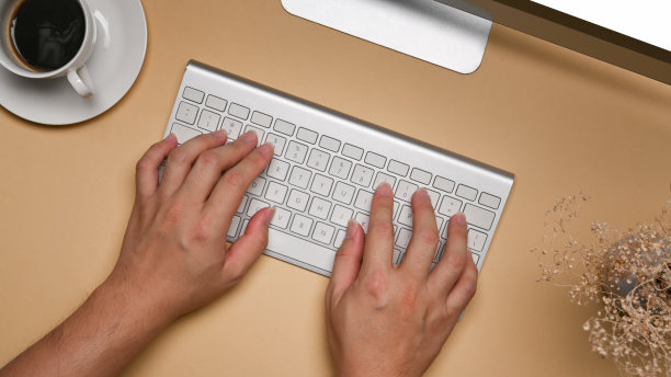 上图是一个年轻人的手在无线键盘上打字。图片下载