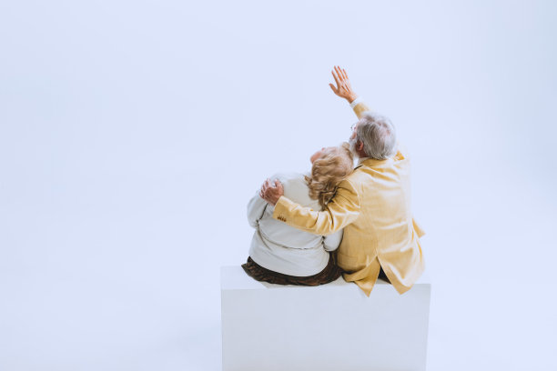 两个人的背影，老女人和大胡子男人穿着复古风格的衣服，70、60年代的时尚，坐在一起孤立的白色工作室背景图片下载