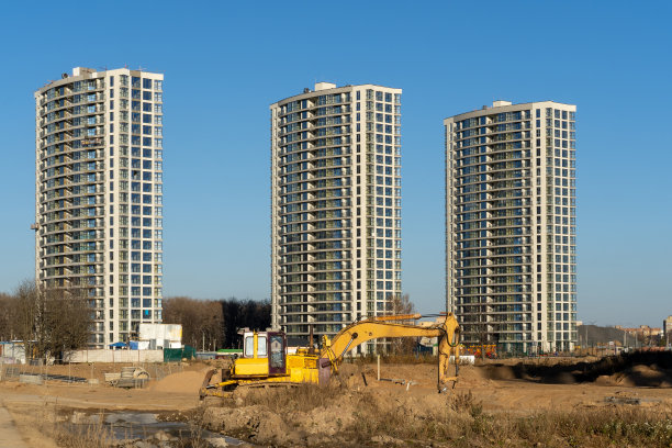 建筑工地和高层建筑的照片和黄色挖掘机在城市里。建筑的概念图片下载