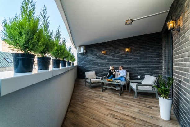 一对年轻夫妇在日落时分的公寓阳台上喝酒。图片下载