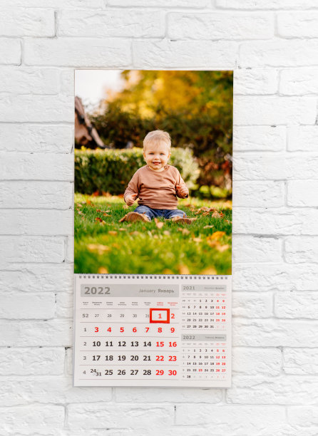 白色砖墙前的日历和孩子的照片。印刷产品图片下载