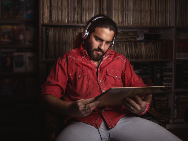 年轻人舒适地坐在椅子上听音乐。图片下载