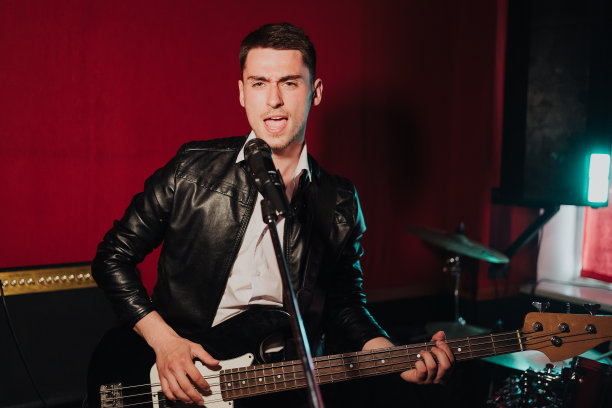 年轻的男性潮人在录音室录制新声音，同时玩电吉他和唱歌图片下载