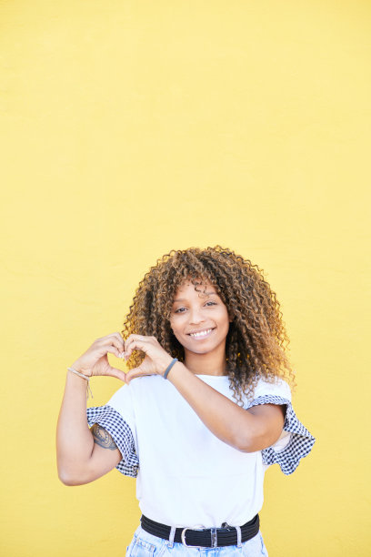 一个非洲裔女人的垂直照片，她的手放在她的心脏。和平与爱的概念图片下载