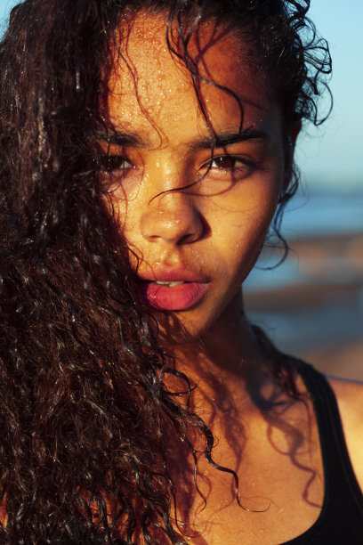 年轻漂亮的女孩亚洲脸卷发在海滩，假期晒黑图片下载