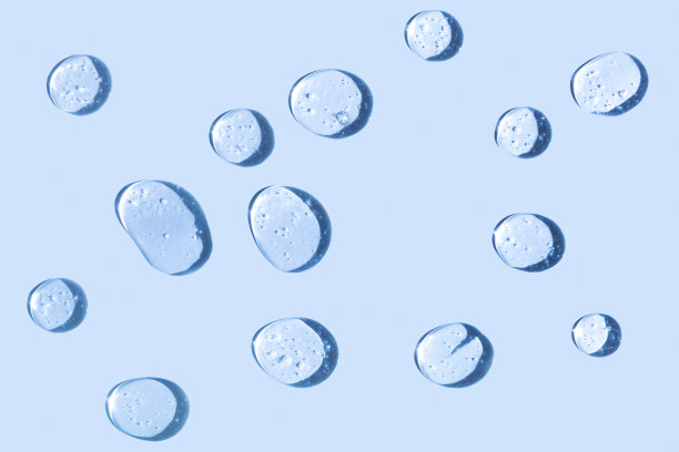 化妆品保湿产品或成分概念。滴凝胶透明液体在一个蓝色的背景。水滴或油关闭。图片下载