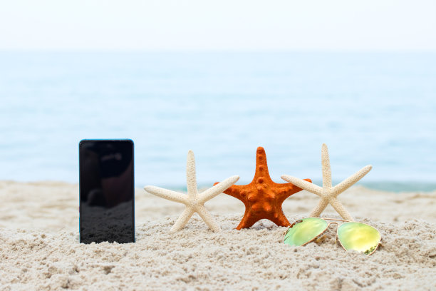 手机和海星就在热带海滩的夏季与复制空间。无论他们在哪里，他们都可以在任何地方互相交流概念。图片下载