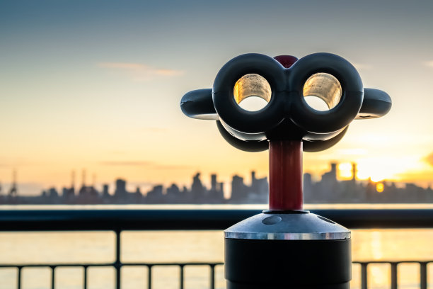 用双筒望远镜观察城市的天际线。图片下载