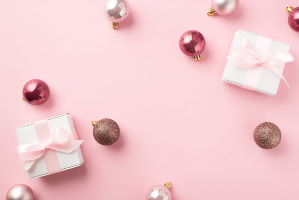 Top view照片的粉红色圣诞树装饰球和白色礼品盒粉红丝带蝴蝶结孤立的粉彩背景图片下载