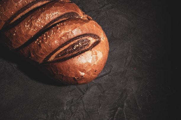 不同寻常的双色新鲜面包在黑色背景上，照片在强光下低调拍摄，特写。图片下载