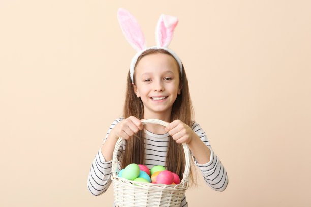 一个可爱的微笑的小女孩的肖像，兔耳朵和复活节彩蛋在手图片下载