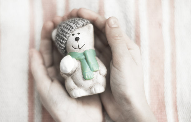 陶瓷可爱的小熊小熊在编织的帽子在一个孩子的手在一个白色的背景。图片下载