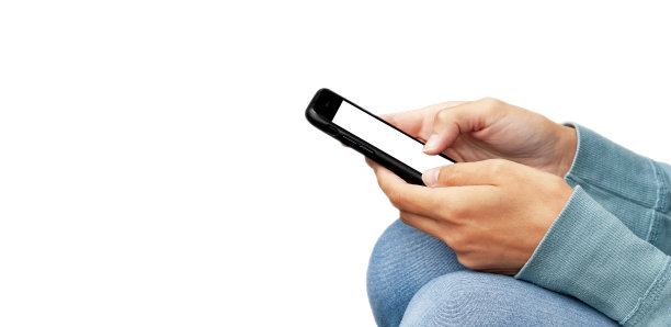 一名匿名年轻女子拿着一个空白屏幕的智能手机坐着，用手机触碰一个空的显示屏，侧视图。宽横幅，复制空间，双手使用手机隔离，剪切图片下载