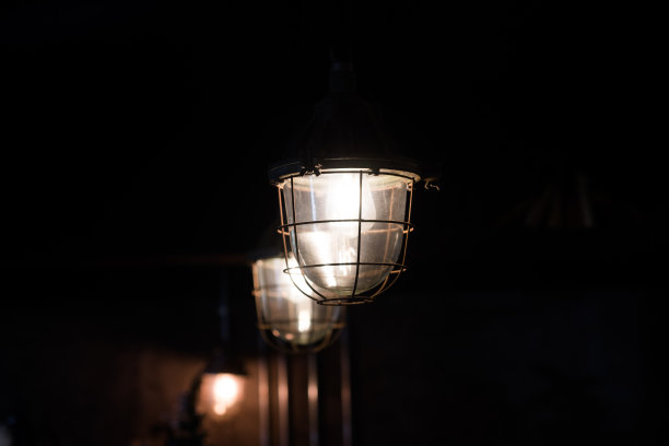 夜晚花园里的灯发出桔黄色的光，灯杆图片下载