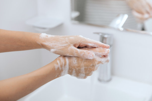 在流动的水龙头下洗手。用肥皂洗手预防冠状病毒，防止在公共卫生间传播冠状病毒的卫生。卫生概念手细节图片下载