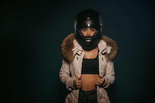 穿着夹克的女人，戴着头盔站在工作室里图片下载