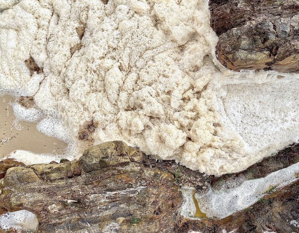 海水泡沫水在海滩岩石和沙子上图片下载