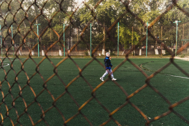 足球领域关闭。男孩跑过足球场。透过格子拍照。秋天。雾图片下载