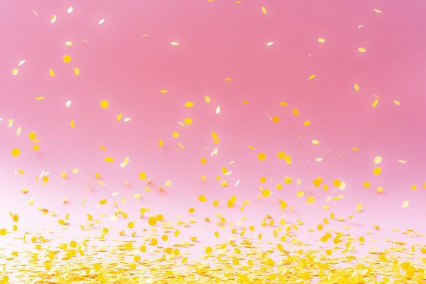黄色的纸屑在粉红色的背景上飞舞图片下载