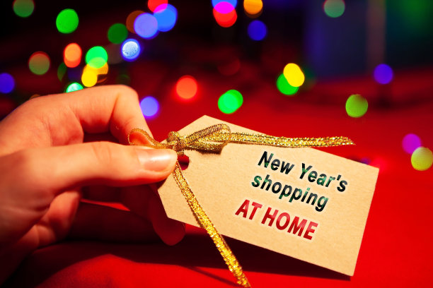 一个女人手里拿着一个标签，上面写着“新年大甩卖”，上面有一个金色的蝴蝶结，特写。图片下载