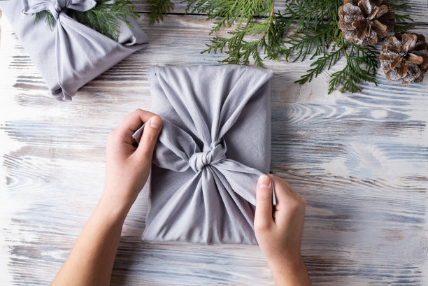 女性用布包裹圣诞礼物，环保理念。图片下载