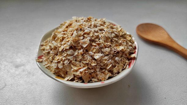 燕麦片放在小碗里，木勺放在灰色背景上。燕麦片图片下载