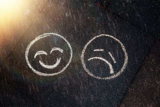 用蜡笔在地上画的微笑和悲伤表情。雨天和晴天。心理和心理健康的概念图片下载