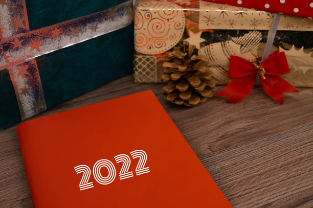以圣诞礼物为背景的木桌上摆放着封面上写着“2022”的书。图片下载
