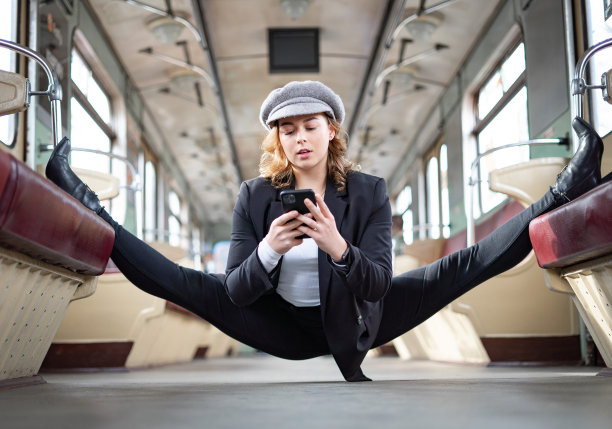 柔韧的女孩坐在地铁车厢的裂缝与智能手机。创意、个性和自信的概念图片下载