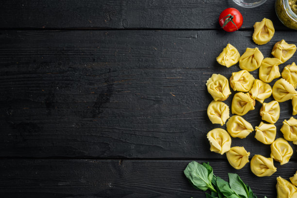 生饺子与罗勒和松香蒜沙司，在黑色木制桌子背景上，俯视图平铺，与文本复制空间图片下载
