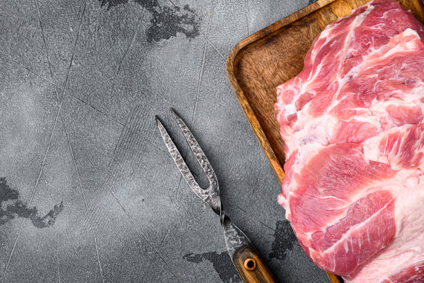 生猪肉颈肉块的排骨，在灰色的石头桌子背景，顶视图平放，与复制空间的文本图片下载