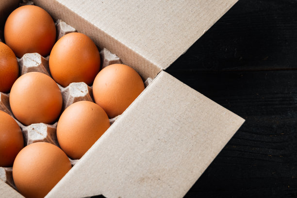 生鸡蛋在鸡蛋盒，在黑色木桌背景图片下载