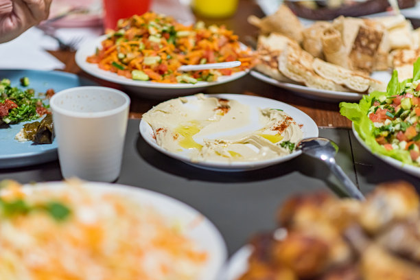 人们一起吃饭。摆满阿拉伯美食的餐桌。鹰嘴豆、沙拉、皮塔饼、酿蔬菜、肉和鸡肉。高品质照片图片下载