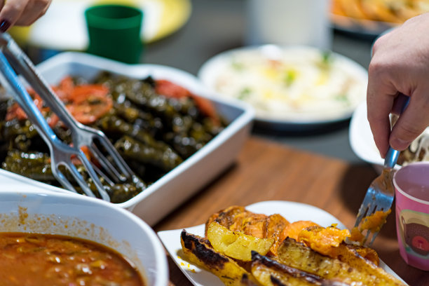 人们一起吃饭。摆满阿拉伯美食的餐桌。鹰嘴豆、沙拉、皮塔饼、酿蔬菜、肉和鸡肉。高品质照片图片下载