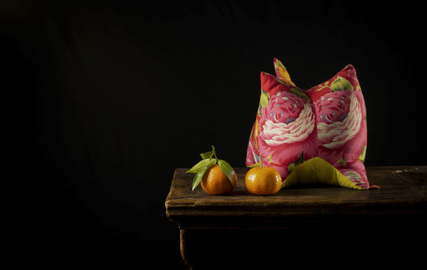 中国民族风格静物画，红色老虎枕，木桌上的陈皮水果，靠黑墙图片下载